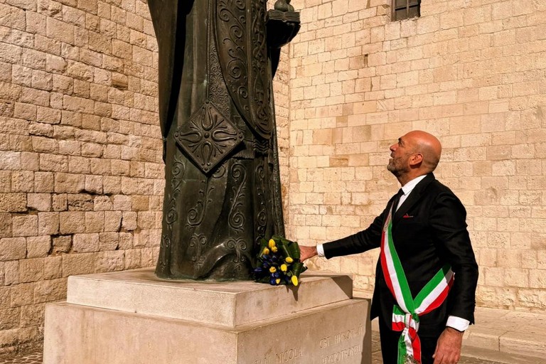 quarto anniversario dellinvasione russa in Ucraina bandiera ucraina sulla facciata di palazzo della Citta sindaco depone dei fiori sotto la statua di san Nicola foto